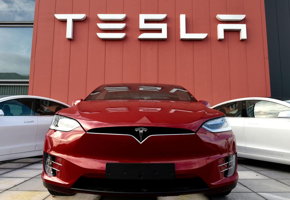 Automobil Tesla pred budovou s logom Tesla